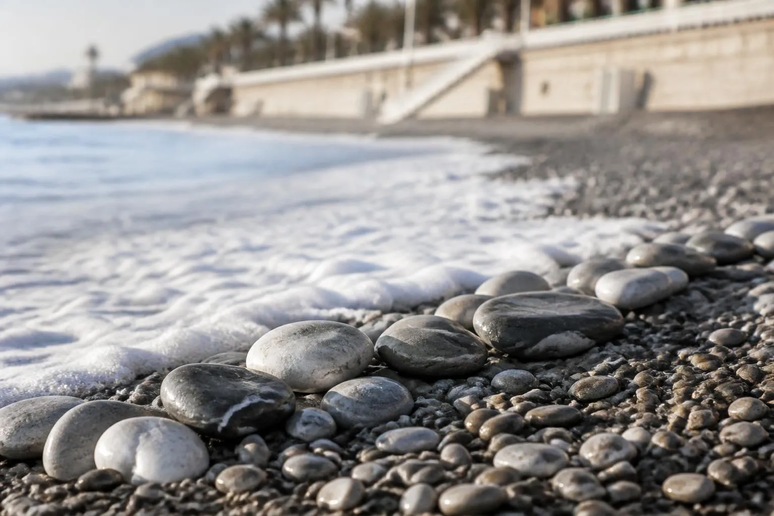 Galets gris et blancs de la plage de Nice, mouillés par une vague qui se retire