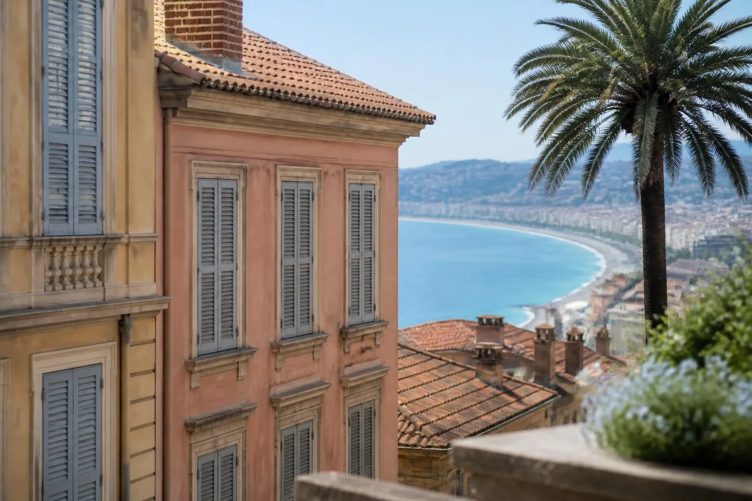 Façades Belle Époque et toits de tuiles d'un quartier de Nice vus depuis une colline, la mer au fond