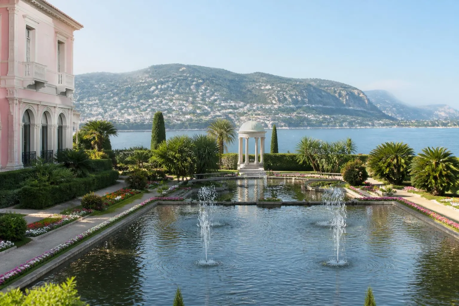 Le grand bassin du jardin à la française de la villa Ephrussi de Rothschild, ses jets d'eau et le temple de l'Amour au fond, la mer des deux côtés